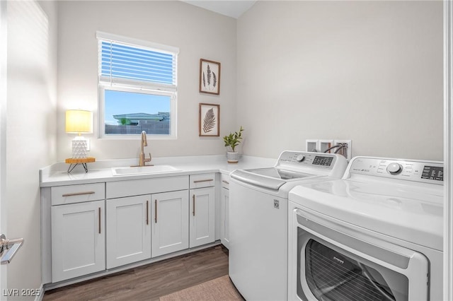 laundry room featuring dark wood-style flooring, cabinet space, a sink, and washing machine and clothes dryer