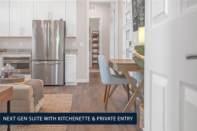 kitchen with light stone counters, appliances with stainless steel finishes, and white cabinetry