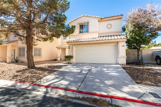 mediterranean / spanish home featuring a garage, fence, concrete driveway, and stucco siding