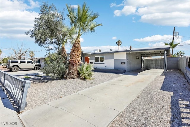 single story home with driveway, an attached carport, fence, and stucco siding