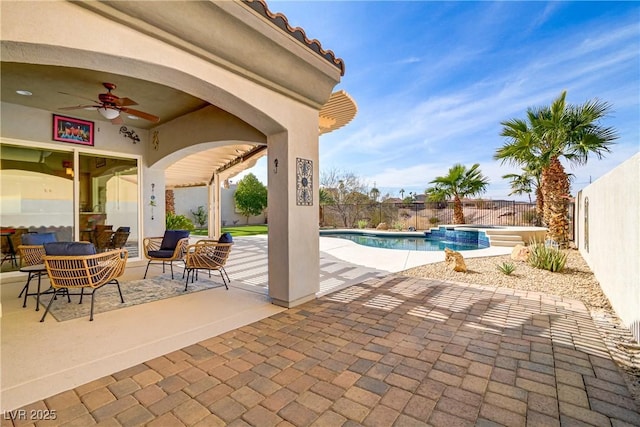 view of patio / terrace featuring a fenced backyard, a pool with connected hot tub, and a ceiling fan