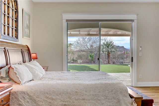 bedroom featuring access to exterior, baseboards, and wood finished floors