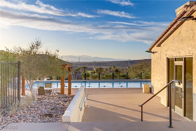 view of patio / terrace with fence, a mountain view, and a community pool