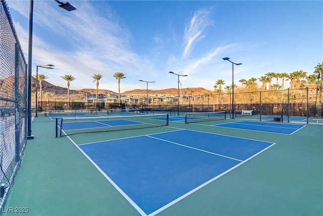 view of tennis court with fence and a mountain view