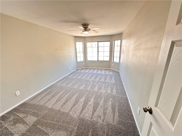 carpeted spare room with ceiling fan and baseboards