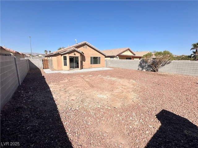 rear view of house featuring a fenced backyard, a patio, and stucco siding