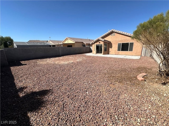 rear view of house featuring a patio area, a fenced backyard, a tile roof, and stucco siding