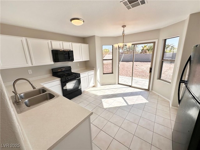 kitchen with pendant lighting, light countertops, visible vents, a sink, and black appliances