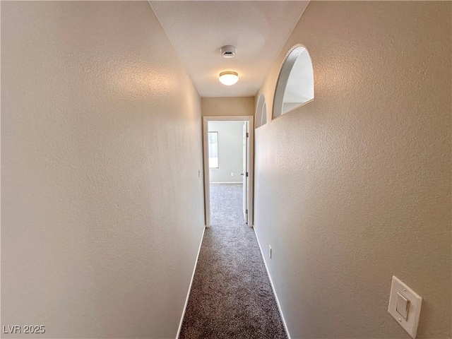 corridor with carpet, baseboards, and a textured wall