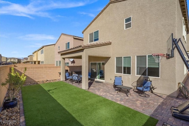 back of house featuring a fenced backyard, a yard, a tiled roof, stucco siding, and a patio area