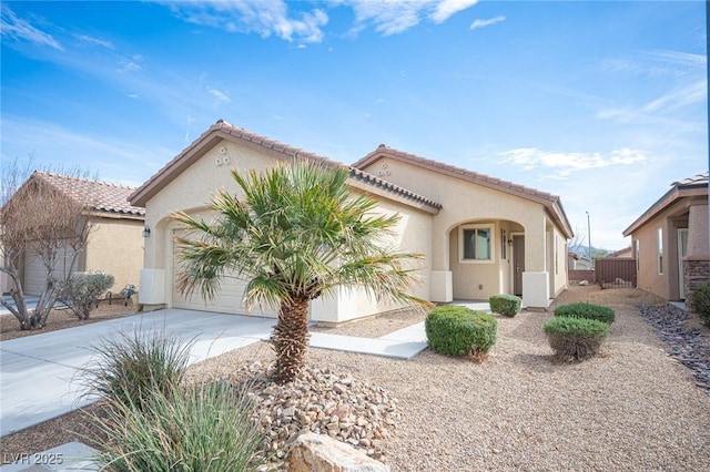 mediterranean / spanish-style home with an attached garage, a tiled roof, concrete driveway, and stucco siding