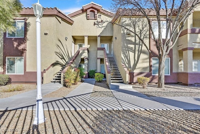 exterior space featuring a tiled roof, stairway, and stucco siding