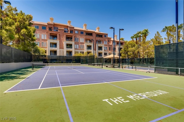 view of tennis court featuring community basketball court and fence