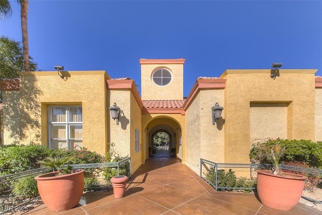 property entrance with a patio area, a tile roof, and stucco siding