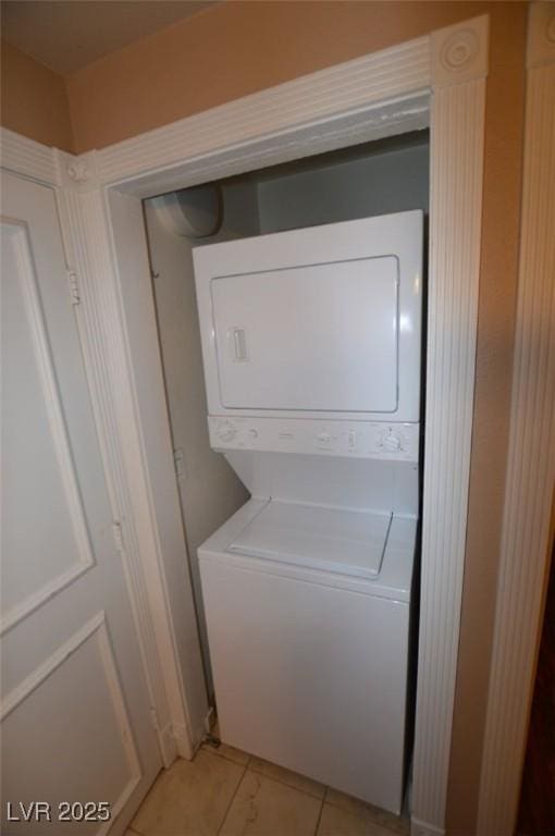 washroom with stacked washer and dryer, laundry area, and light tile patterned flooring