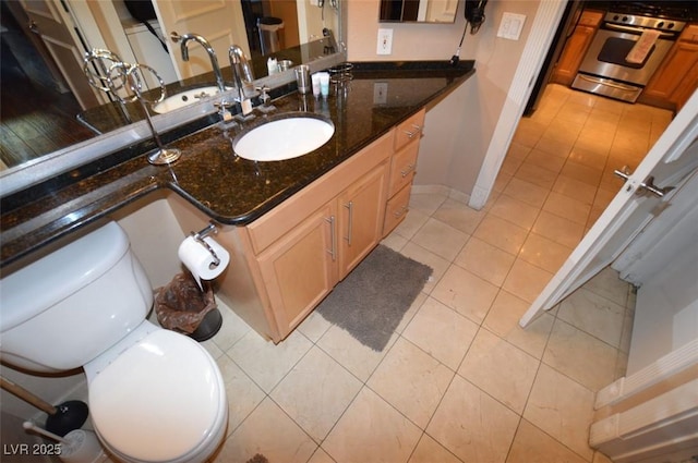 bathroom featuring tile patterned flooring, baseboards, vanity, and toilet