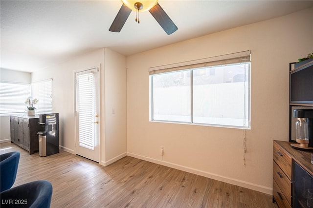 interior space featuring light wood finished floors, baseboards, and a ceiling fan