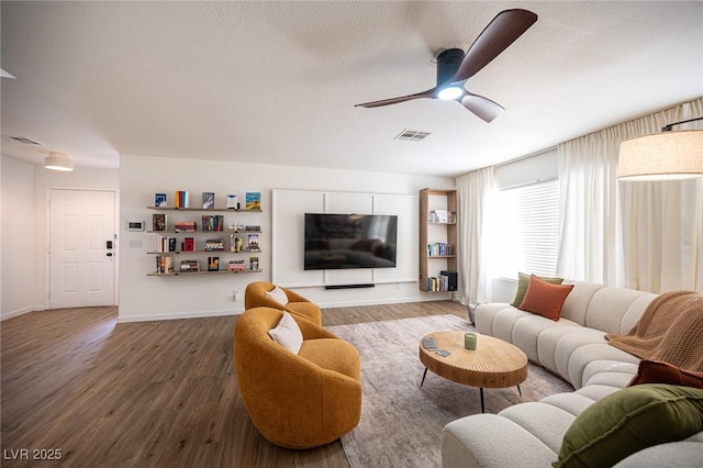 living area with a ceiling fan, visible vents, a textured ceiling, and wood finished floors