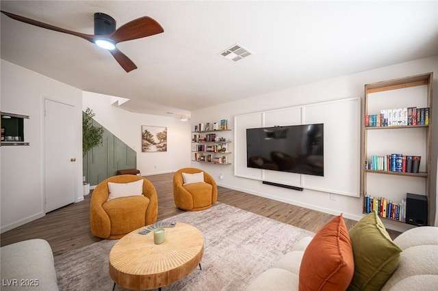 living area featuring visible vents, ceiling fan, baseboards, and wood finished floors