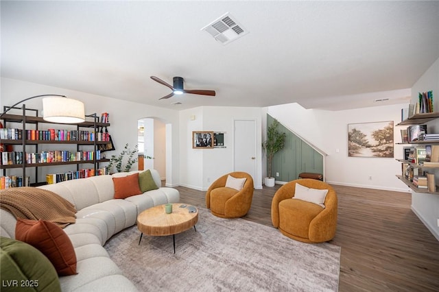 living area featuring baseboards, visible vents, arched walkways, dark wood-style floors, and ceiling fan