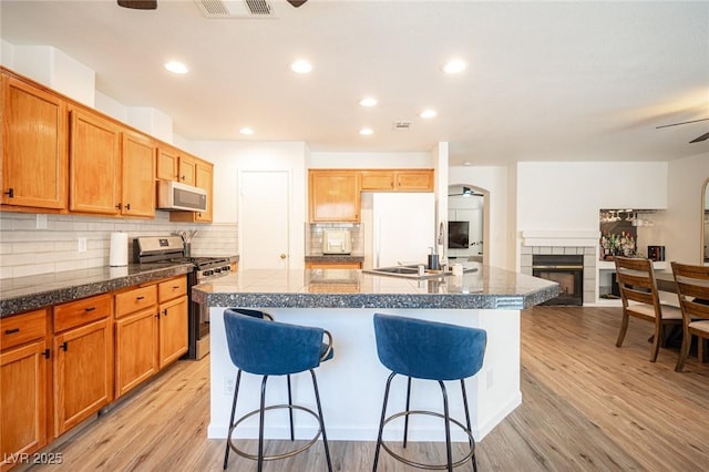 kitchen featuring an island with sink, white appliances, a breakfast bar area, and open floor plan