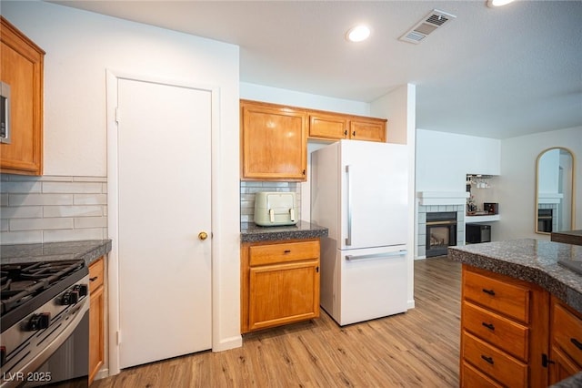 kitchen with freestanding refrigerator, visible vents, dark countertops, and a tile fireplace