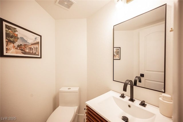 bathroom with toilet, visible vents, and vanity