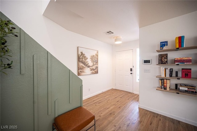 foyer with wood finished floors, visible vents, and baseboards