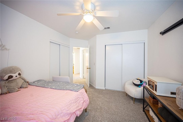 bedroom with multiple closets, light colored carpet, ceiling fan, and visible vents