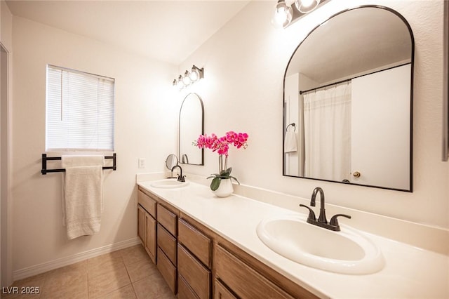 bathroom featuring tile patterned flooring, a sink, baseboards, and double vanity