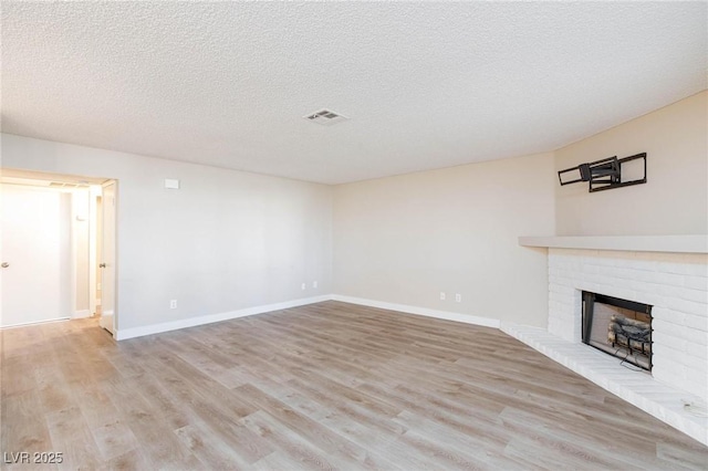 unfurnished living room with light wood finished floors, baseboards, a fireplace, and visible vents