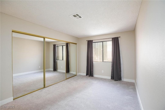 unfurnished bedroom with carpet floors, visible vents, and a textured ceiling