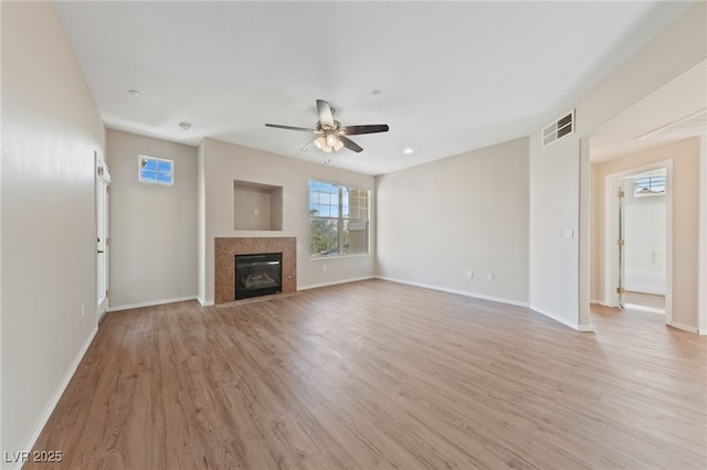 unfurnished living room featuring light wood-type flooring, a fireplace, visible vents, and baseboards