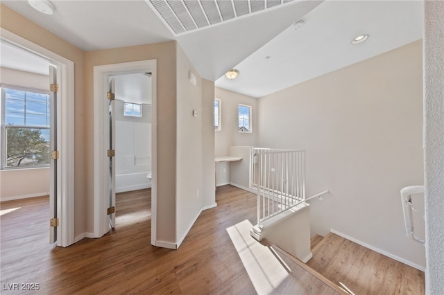 hallway featuring light wood-style flooring, plenty of natural light, an upstairs landing, and baseboards