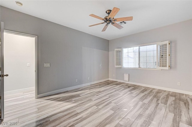 empty room featuring ceiling fan, light wood finished floors, visible vents, and baseboards