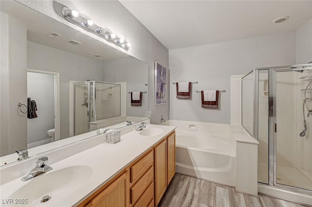 bathroom featuring toilet, a garden tub, a sink, and a stall shower