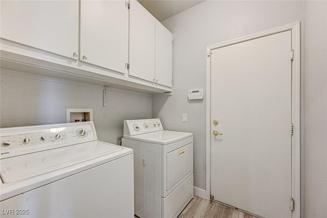 washroom featuring cabinet space, light wood finished floors, and separate washer and dryer