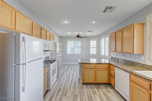 kitchen with visible vents, light wood-style flooring, light brown cabinets, white appliances, and a peninsula