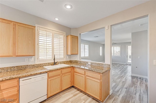 kitchen with light wood finished floors, light stone countertops, white dishwasher, light brown cabinets, and a sink