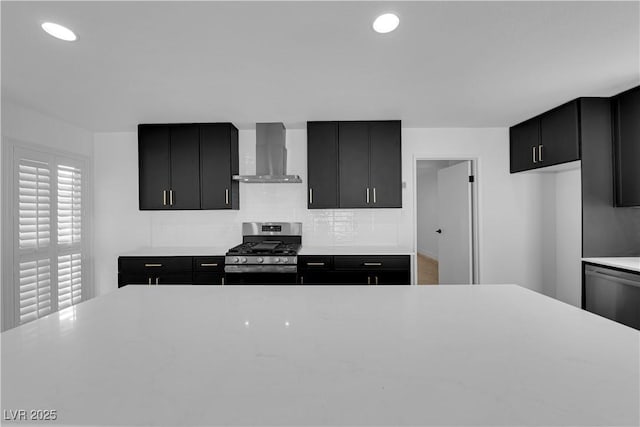 kitchen featuring wall chimney range hood, stainless steel appliances, and dark cabinets