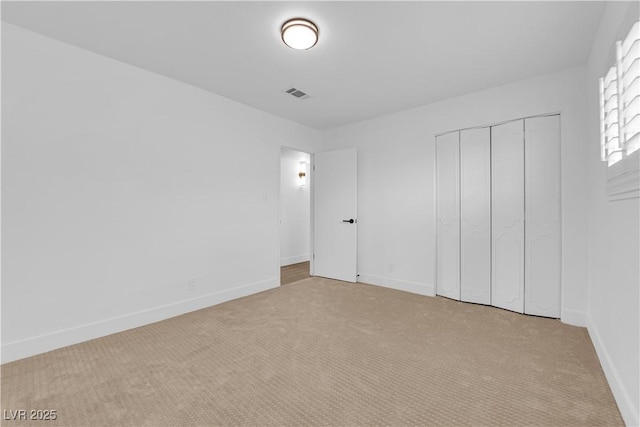 unfurnished bedroom featuring carpet floors, a closet, visible vents, and baseboards