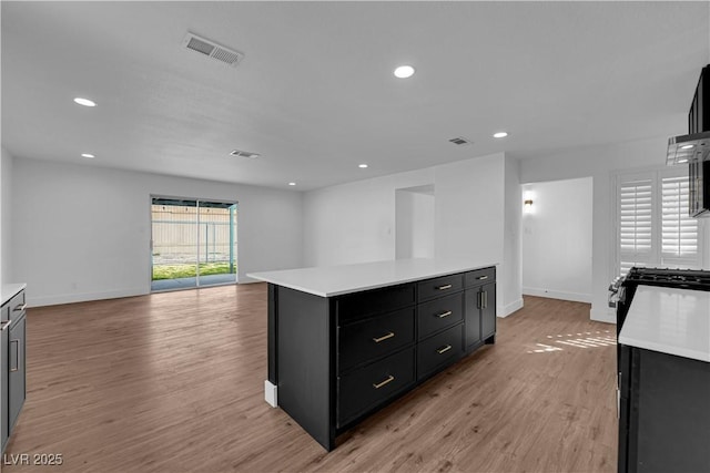 kitchen featuring dark cabinets, light countertops, visible vents, and light wood finished floors