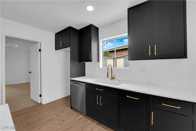 kitchen featuring dark cabinets, a sink, light countertops, backsplash, and dishwasher