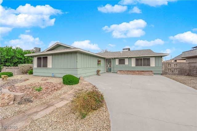 ranch-style house with concrete driveway, board and batten siding, and fence