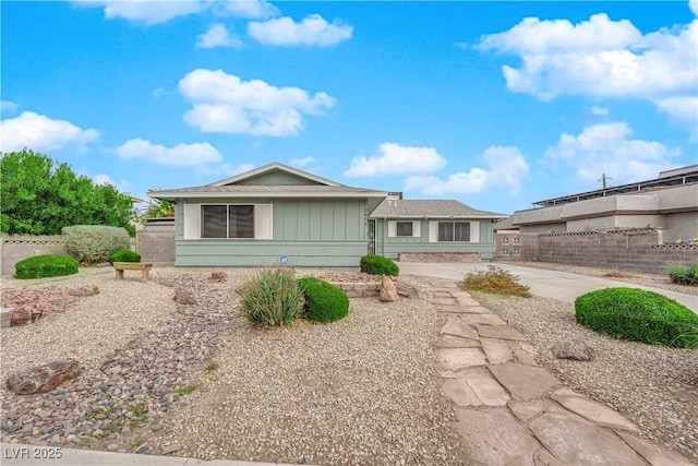 view of front of property with concrete driveway, board and batten siding, and fence