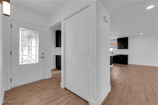 entryway with light wood-type flooring, baseboards, and recessed lighting