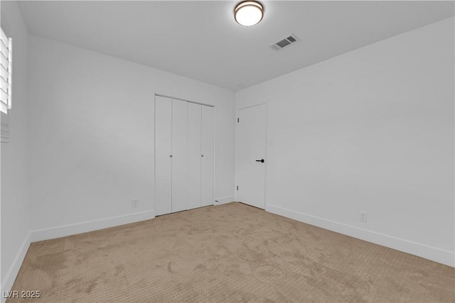 carpeted spare room featuring baseboards and visible vents