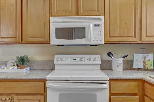 kitchen with light brown cabinets, white appliances, and light countertops