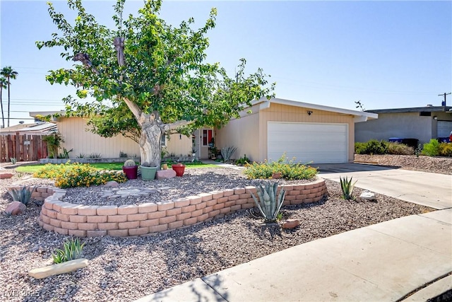 mid-century modern home featuring a garage, concrete driveway, and fence