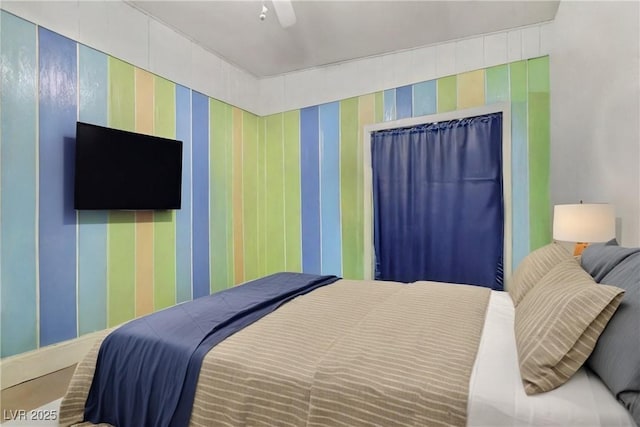 bedroom with a ceiling fan and wallpapered walls